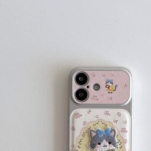 a smartphone with a pink and white floral design on the back cover and a cat image on the front cover.