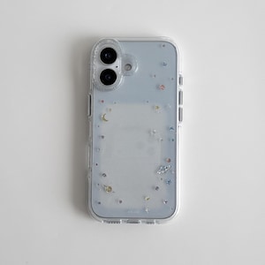 Puede incluir: Funda transparente para teléfono con un fondo azul claro y un diseño de constelación. La funda presenta pequeñas estrellas de colores, planetas y lunas crecientes. La funda tiene un borde transparente y un recorte para la cámara.
