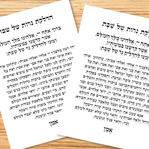May include: Two white printed papers with Hebrew text. The text is in black and is centered on the pages. The papers are on a light wood surface.