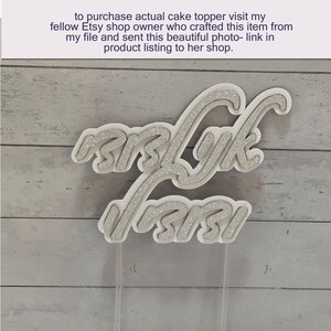 May include: A white and silver glitter cake topper with the words "Mrs. Lyk Forsi" in a cursive font. The topper is on clear plastic sticks, ready to be placed on a cake. The text "to purchase actual cake topper..." is visible.