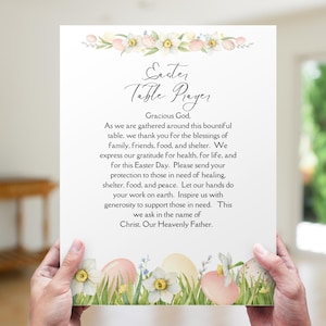 Könnte beinhalten: Eine weiße Oster-Tischgebetkarte mit Blumen- und Eierillustrationen. Die Karte enthält den Text "Oster-Tischgebet" und ein Gebet für den Ostertag. Die Karte wird von einer Person gehalten.