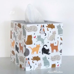 May include: A white tissue box cover with a gray base. The cover is decorated with a pattern of colorful cats. The text "Laurie B Creations" is printed on the bottom of the box.