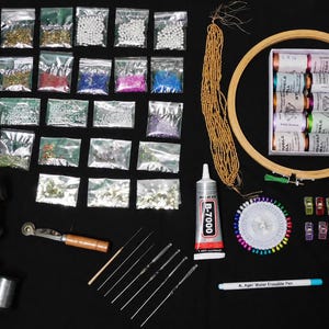 May include: A craft supply kit containing twenty small plastic bags of assorted beads, a wooden embroidery hoop, a box of eight spools of thread, a tube of B-7000 glue, a pin cushion, sewing clips, needles, spools of metallic thread, and a water erasable pen.
