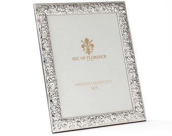 May include: A silver picture frame with an ornate design. The frame has a white mat and a label that reads "SEC OF FLORENCE" and "ARGENTO MASSICCIO 925".