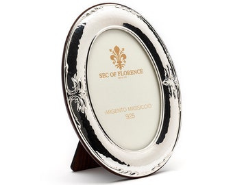 Puede incluir: Marco de fotos ovalado de plata con un diseño ornamentado y un soporte. El marco tiene el texto "SEC OF FLORENCE" y "ARGENTO MASSICCIO 925".