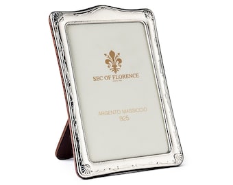 Puede incluir: Un marco de fotos de plata con un diseño ornamentado y un soporte de madera. El marco tiene el texto "SEC OF FLORENCE" y "ARGENTO MASSICCIO 925" en él.