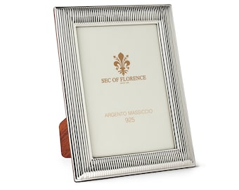 May include: A silver picture frame with a striped design. The frame is made of solid silver and has a wooden stand. The frame is labeled "Sec of Florence" and "Argento Massiccio 925".