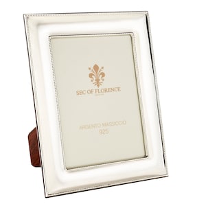 Puede incluir: Un marco de fotos de plata con un borde biselado y un borde decorativo. El marco tiene un soporte en la parte posterior y dice "SEC of FLORENCE since 1998" y "ARGENTO MASSICCIO 925" en la parte delantera.