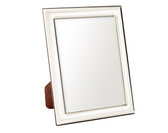 May include: A white picture frame with a silver trim and a wooden stand. The frame is empty.