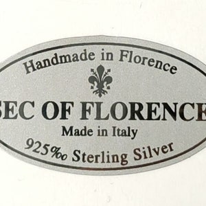 Pode incluir: Etiqueta oval prateada com o texto "Handmade in Florence" e "SEC OF FLORENCE Made in Italy 925% Sterling Silver". Uma flor-de-lis est&aacute; no centro da etiqueta.