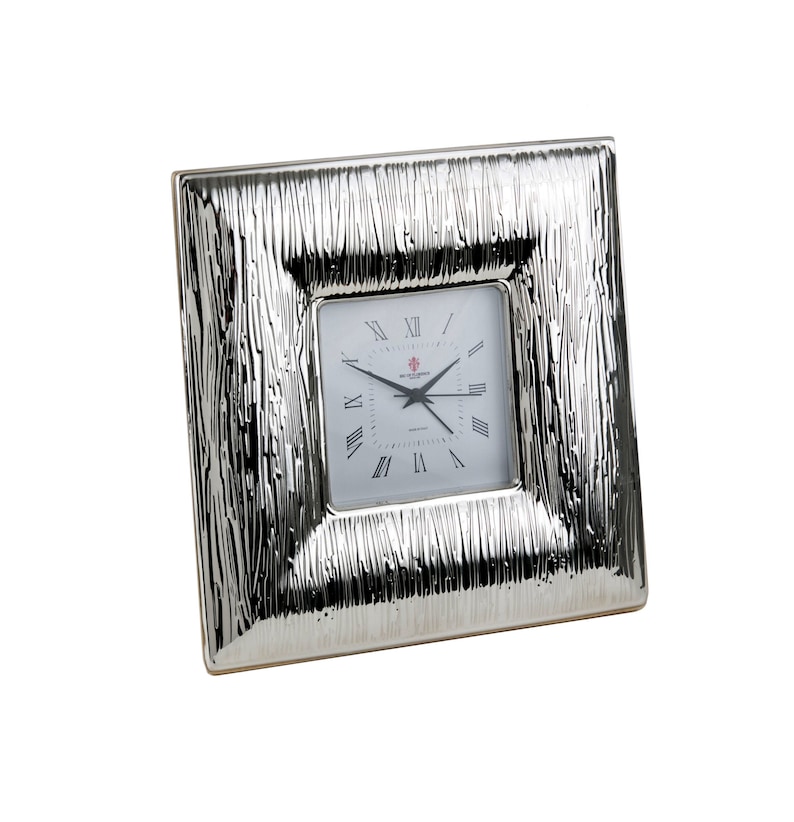 May include: Silver square clock with a textured frame and Roman numeral markings on the face.