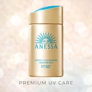 Op de afbeelding: Een goudkleurige zonnebrandcrèmefles met een blauwe dop. De fles toont de merknaam "ANESSA" in blauw, samen met de tekst "PERFECT UV SUNSCREEN SKINCARE MILK SPF50+" en "PREMIUM UV CARE."
