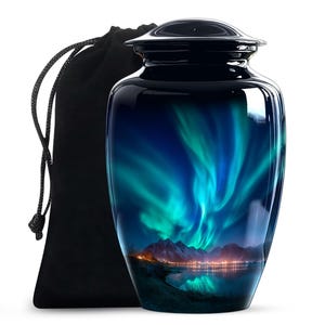 May include: A glossy, dark blue cremation urn with a vibrant depiction of the Northern Lights. The design features swirling green and blue lights over a mountain range and a reflective lake. Includes a black velvet bag.