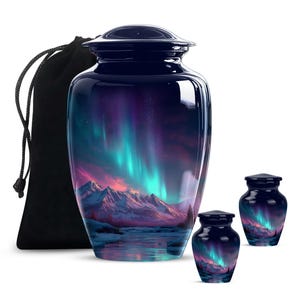 Peut inclure: Une urne funéraire bleu marine brillante, ornée d'un paysage de montagnes et d'aurores boréales aux tons violets, turquoise et roses. Comprend deux petites urnes souvenirs assorties et un sac noir à cordon.
