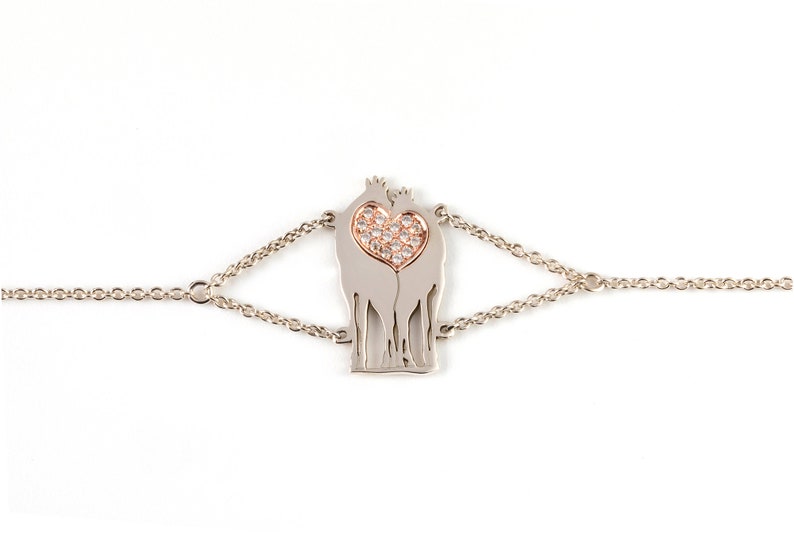 White Gold Bracelet with thin link chain, featuring a pair of Giraffes in love. Standing next to each other with their faces together thus forming a heart shape between them with their long necks. The heart is in rose gold and filled with diamonds.