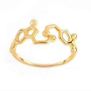 A ring combining the Serotonin and Dopamine hormones, in Yellow Gold with polished finish. The two molecules are side by side across a rounded band.