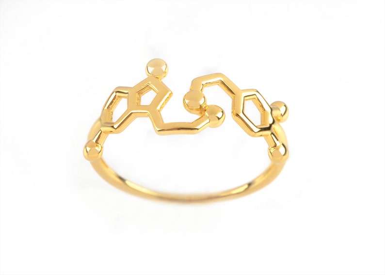 A ring combining the Serotonin and Dopamine hormones, in Yellow Gold with polished finish. The two molecules are side by side across a rounded band.