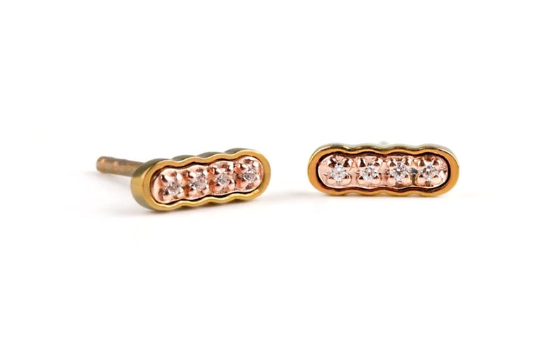 Curly bar stud earrings made from Pink Gold colored Titanium in the external part & pin, surrounding the solid gold Rose Gold in its curly center. This is set with tiny white diamonds, 4 in total on each earring. Polished finish.