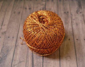 May include: A ball of metallic gold yarn with a shiny finish.