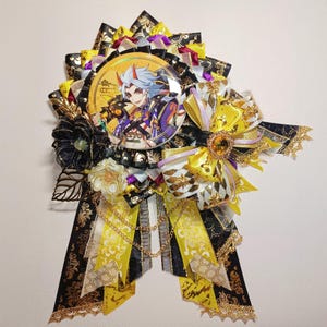 May include: A decorative badge with an anime character image at its centre, encircled by black, yellow, and gold ribbons. The badge incorporates floral elements, gold edging, and a decorative chain.