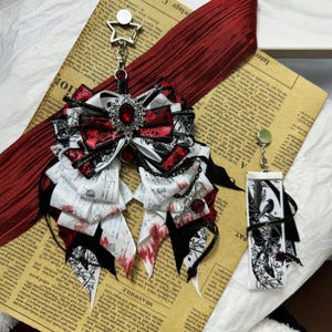 Puede incluir: Un conjunto de accesorios para el cabello de estilo gótico con un lazo grande con detalles en rojo y negro, adornado con una joya central y colgantes. Incluye un dije rectangular a juego con una ilustración en blanco y negro. Sobre un fondo de periódico vintage.