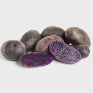 May include: A collection of purple potatoes, some whole and others cut in half to reveal their vibrant purple flesh. The potatoes have a dark, earthy exterior and are arranged on a white surface.