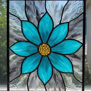 May include: Stained glass panel featuring a large turquoise flower with a golden center. The flower is set against a background of gray and white glass, all framed in black. The panel is likely a decorative window piece.