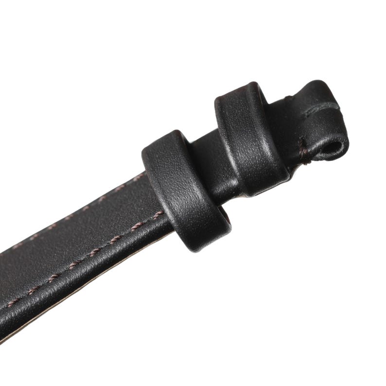 Op de afbeelding: Close-up van een zwarte leren riem met een gesp. De riem is gestikt met een contrasterende draad en heeft een lus en een gesp voor verstelling. Het leer ziet er glad uit en het algehele ontwerp is minimalistisch.