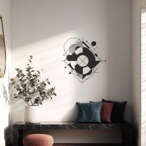 May include: A contemporary black geometric wall sculpture with a circular motif and intersecting lines, mounted on a white wall. Below, a black marble bench holds three velvet cushions in teal, burgundy, and black. A white vase with foliage and a pink ottoman complete the stylish interior.
