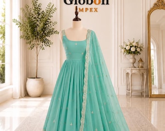 Peut inclure: Une robe anarkali turquoise longue jusqu'au sol avec un corsage sans manches à encolure carrée, une jupe plissée et une dupatta transparente assortie. Le vêtement est orné de broderies argentées complexes et de miroirs sur l'ourlet.