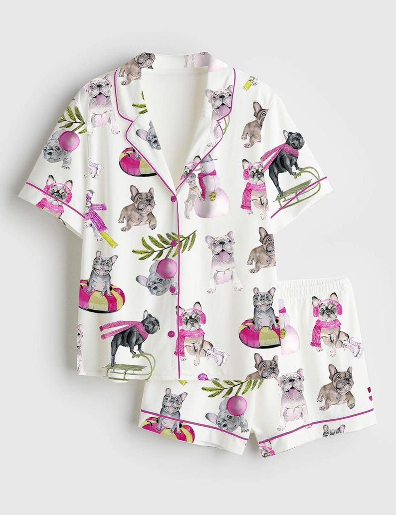 May include: White pajama set with a repeating pattern of French bulldogs in various poses. The short-sleeved top and shorts are trimmed with pink piping. The bulldogs are wearing scarves and hats.