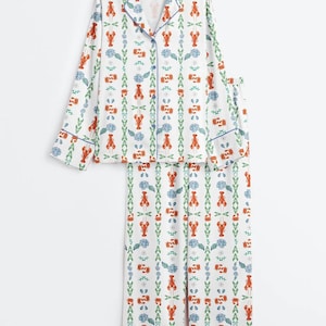 May include: White pajama set with a repeating pattern of red lobsters, blue flowers, and green foliage. The set includes a button-down top with blue trim and matching pants. The pajamas are made of a soft, lightweight fabric.