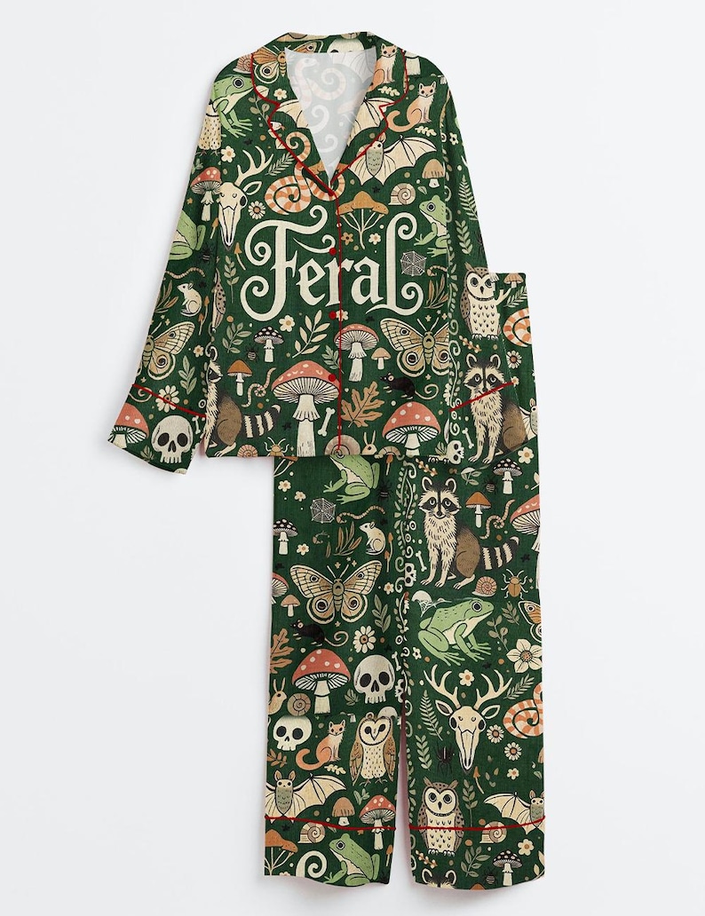 Op de afbeelding: Groene pyjamaset met een grillige bosprint met paddenstoelen, vlinders en bosdieren. Het woord "Feral" staat op de top gedrukt. De set heeft rode bies.