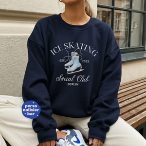 Könnte beinhalten: Marineblaues Sweatshirt mit dem Text "ICE SKATING Social Club BERLIN" und einer Illustration von Schlittschuhen. Das Sweatshirt hat einen Rundhalsausschnitt und lange Ärmel. Der Text "EST. 2025" ist ebenfalls enthalten.