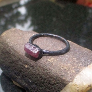 Puede incluir: Un anillo de plata sencillo con una piedra preciosa rosa engastada en la banda.