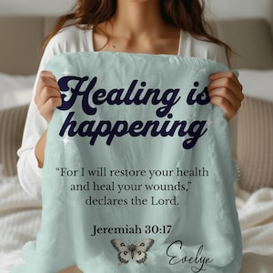 May include: A light blue plush blanket with the words "Healing is happening" in dark blue script. The blanket also features a quote from Jeremiah 30:17 and a butterfly illustration.