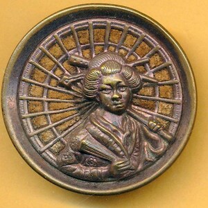 May include: An antique brass button with a detailed relief of a geisha. The geisha is shown with an elaborate hairstyle and traditional clothing, set against a backdrop of a stylized sunburst design. The button is circular in shape.