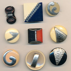 Könnte beinhalten: Eine Sammlung von Vintage-Knöpfen in verschiedenen Formen und Designs. Die Knöpfe weisen eine Reihe von Farben auf, darunter Schwarz, Rot, Blau und Creme, mit silberfarbenen Metallakzenten. Einige Knöpfe haben geometrische Muster, andere abstrakte Formen.