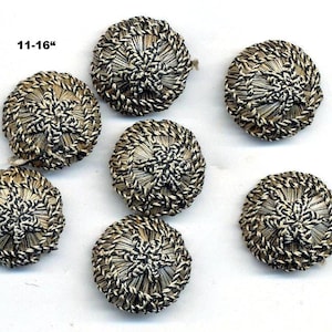 May include: Seven round buttons featuring a metallic gold and black woven cord design with a central star-like pattern. The buttons are arranged in a cluster, and the text 11-16" is visible in the upper left corner, indicating the size of the items.