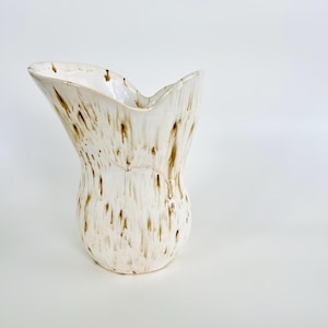 以下が含まれることがあります： 白のセラミックマグカップ、黒いハンドルと手書き風の「But First, Coffee」の文字。マグカップは白い表面に置かれています。マグカップの高さは10cmです。