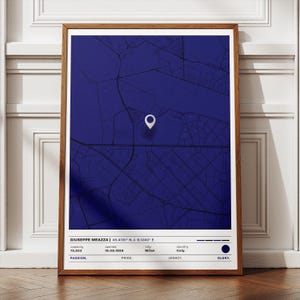 May include: A framed map print in shades of blue, featuring a white location marker. The print includes text at the bottom with details about Giuseppe Meazza stadium, including its capacity, opening date, city, and country. The words "Passion, Pride, Legacy, Glory" are also displayed.
