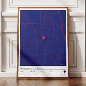 May include: A framed print featuring a blue and red map of Wrigley Field in Chicago. The map shows street grids and the stadium's location. Text at the bottom includes the stadium's name, coordinates, capacity, opening date, city, state, and the words "History, Passion, Pride, Legacy."