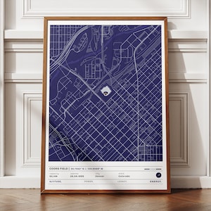 Può includere: Una stampa incorniciata con una mappa dettagliata del Coors Field a Denver, Colorado, con linee bianche su sfondo blu scuro. La stampa include il nome dello stadio, le coordinate, la capacità e la data di apertura. La cornice è di colore marrone caldo.