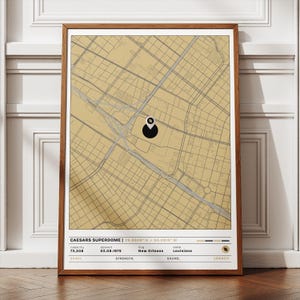 Op de afbeelding: Een ingelijste print met een kaart van New Orleans, Louisiana, in sepia tinten. De kaart toont de Caesars Superdome, met zijn naam en coördinaten. Extra details zijn de capaciteit van het stadion, de openingsdatum en de staat.