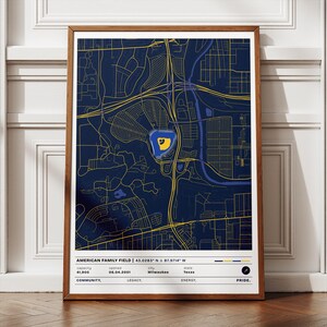 May include: A framed print featuring a detailed map of an area, with a stadium highlighted in yellow and blue. The print includes text identifying the location as American Family Field, with coordinates, capacity, and other details. The overall color scheme is navy blue and yellow.