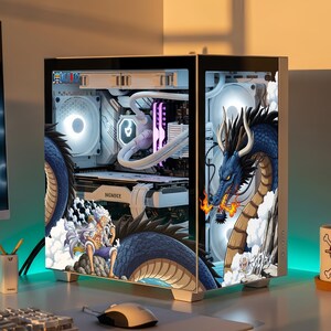 Könnte beinhalten: Ein weißes Computergehäuse mit einer One Piece Anime-Grafikfolierung. Das Seitenteil zeigt einen blauen Drachen und eine Figur mit weißen Haaren. Im Inneren sind weiße Kühlkomponenten, eine weiße Grafikkarte und leuchtende Lüfter zu sehen.