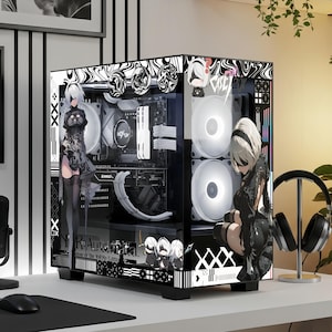 May include: A custom computer case featuring NieR:Automata graphics, including character illustrations of 2B, black and white abstract patterns, and the game title text. The case has a transparent side panel revealing internal cooling fans and components.
