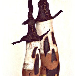 May include: Two tall, cylindrical figures with white, orange, and yellow color-blocked bodies featuring carved-out, dark-colored facial expressions. Each figure wears a tall, pointed, dark-colored hat adorned with a vertical row of small, round buttons.