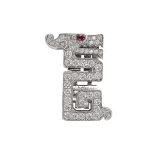 Könnte beinhalten: Ein diamantbesetzter Anhänger in Form eines stilisierten Drachen. Der Anhänger hat ein rotes Edelsteinauge und ist vor einem weißen Hintergrund platziert. Das Design ist aufwendig und detailliert und zeigt das Funkeln der Diamanten.