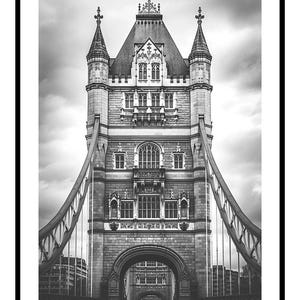 Può includere: Fotografia in bianco e nero del Tower Bridge di Londra, incorniciata in nero. L'immagine mette in risalto l'architettura dettagliata del ponte, con le sue torri, archi e cavi di sospensione. Il cielo nuvoloso aggiunge un effetto drammatico.